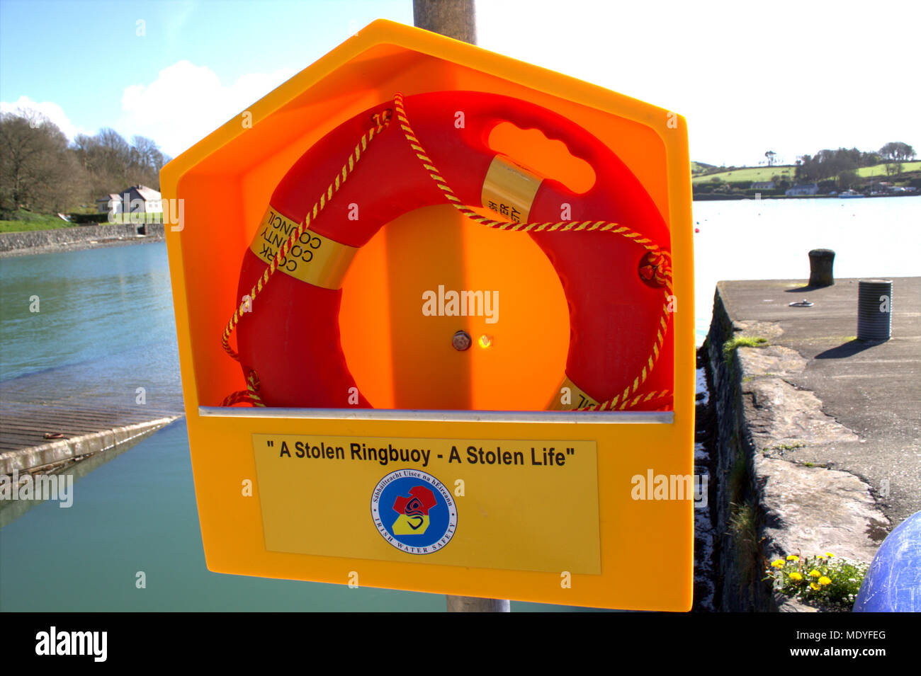 brand new lifebuoy ring mounted on a pole by the side of a slipway and pier, ready to be used to stop people drowning. Stock Photo