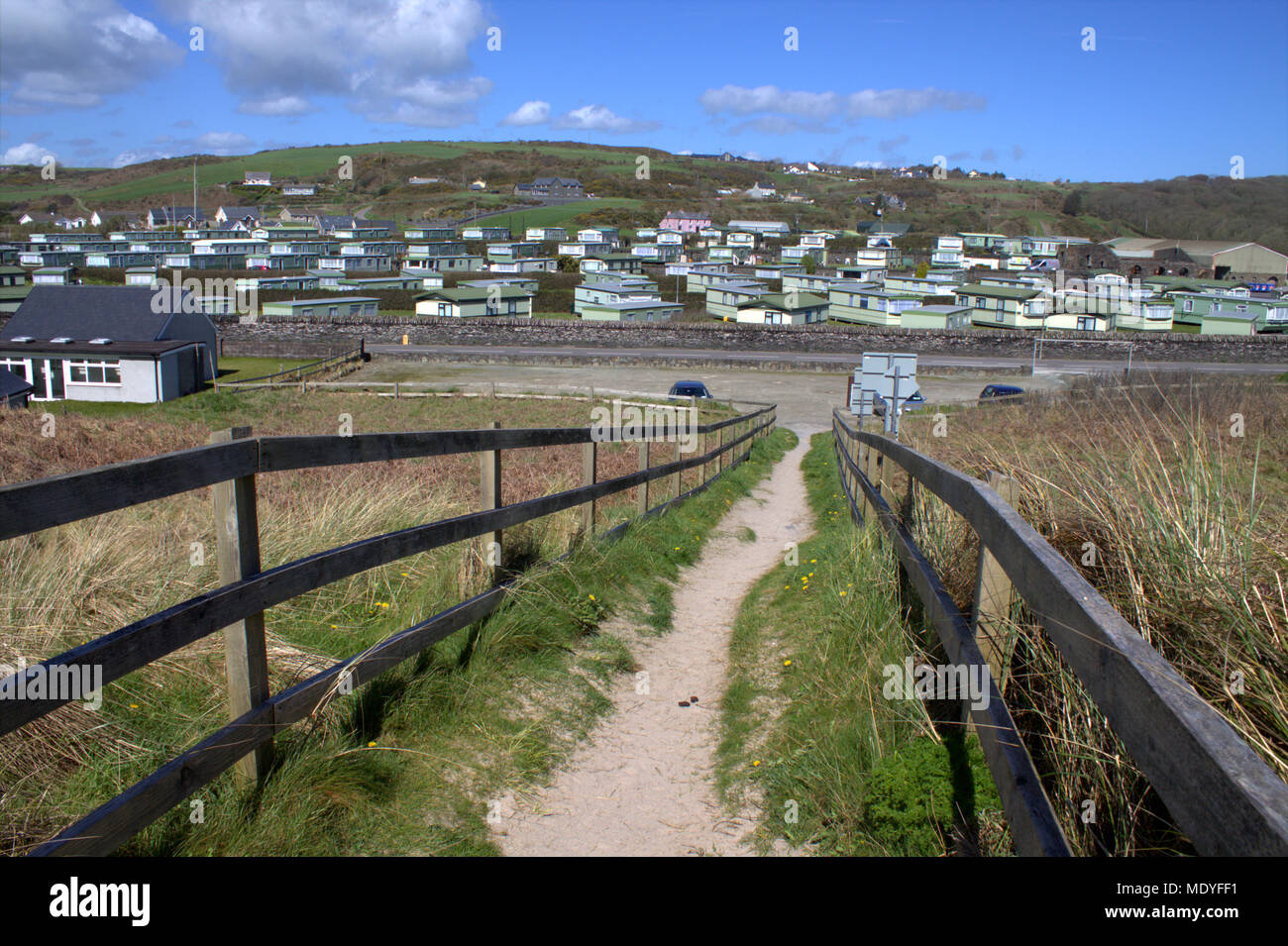 sandy footpath with wooden railings leading back from Owenahincha Beach in county cork, ireland to a large caravan park, a tourist and holiday resort. Stock Photo