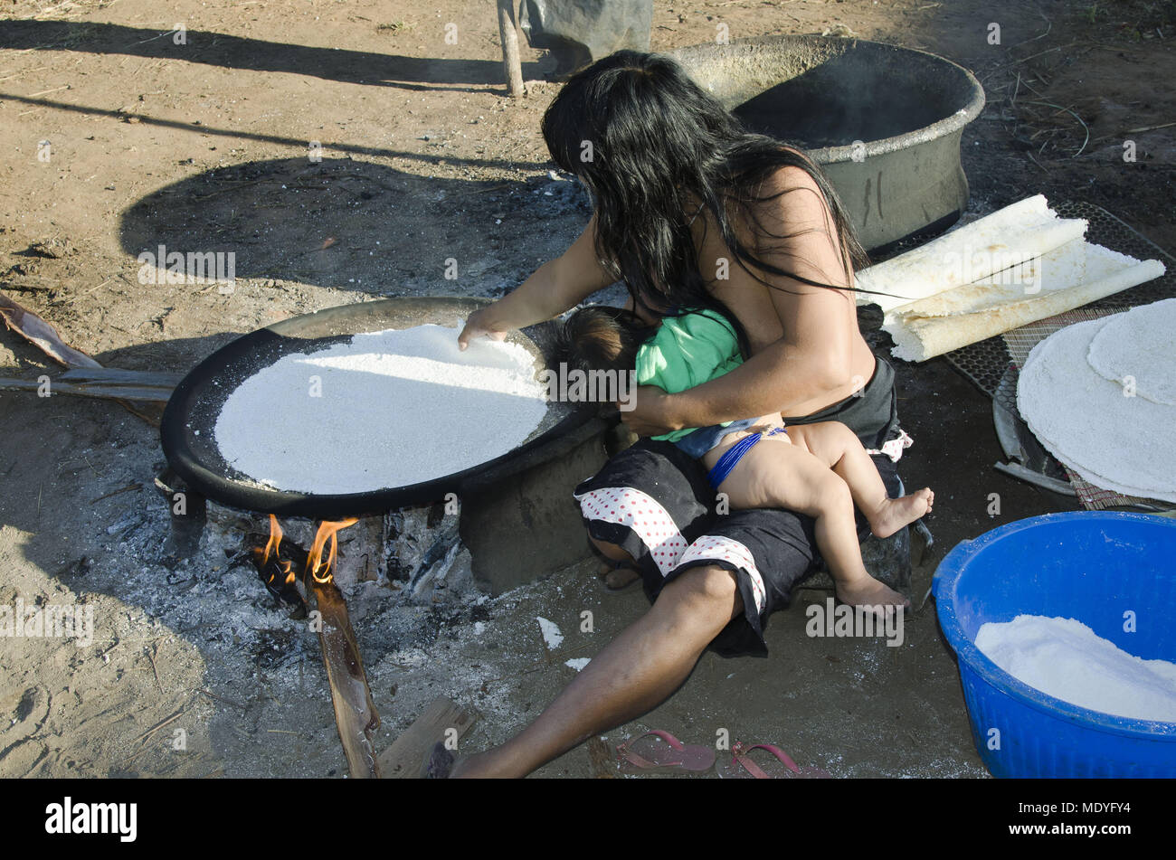 indias village Aiha ethnicity Kalapalo Brazileastfed child while making tapioca cassava Stock Photo
