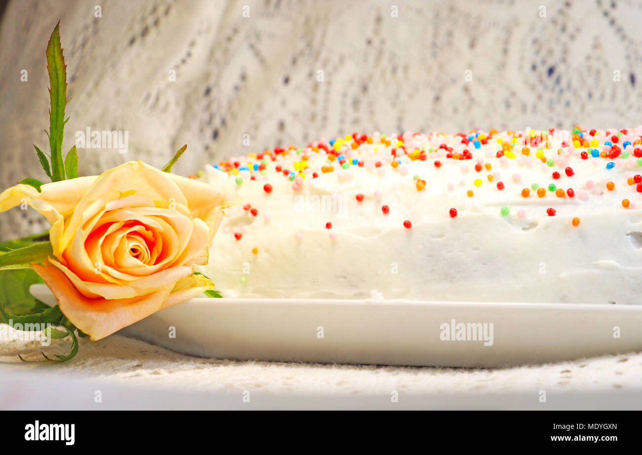 A white cake decorated with colored candies on a tray on a table with a lace tablecloth Stock Photo