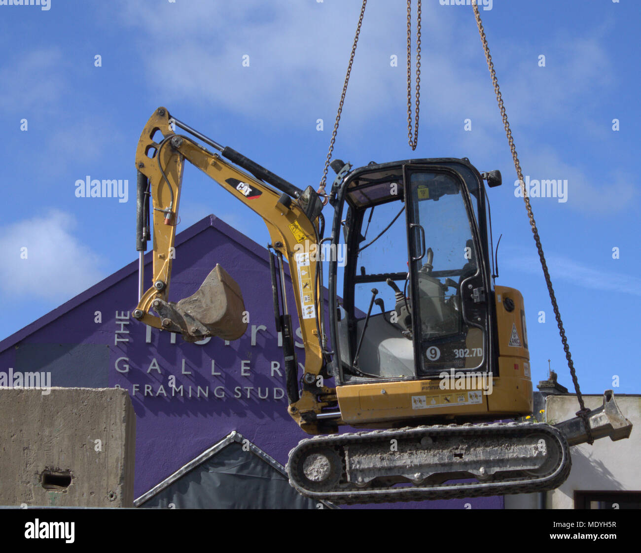 mini digger, construction machine hanging by chains under a crane arm ready to be swung into a new working position. Stock Photo
