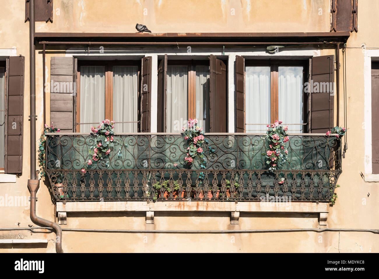 three window with balcony decorated by rose flowers in Venice, Italy Stock Photo