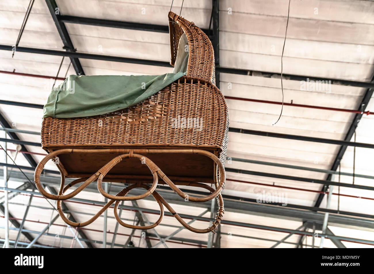 large wicker pram hangs from the ceiling Stock Photo