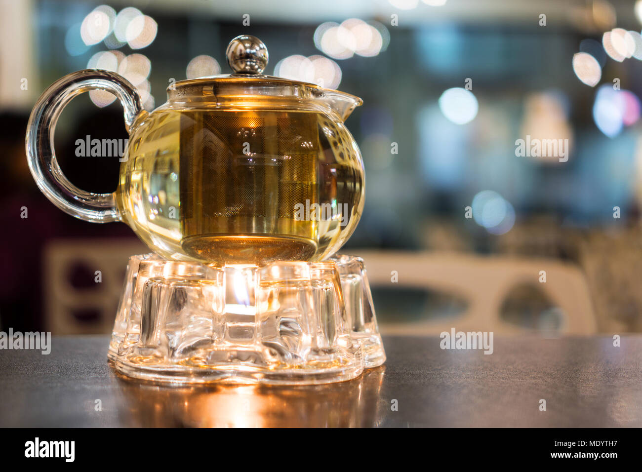 Hot teapot with warmer on wood table Stock Photo
