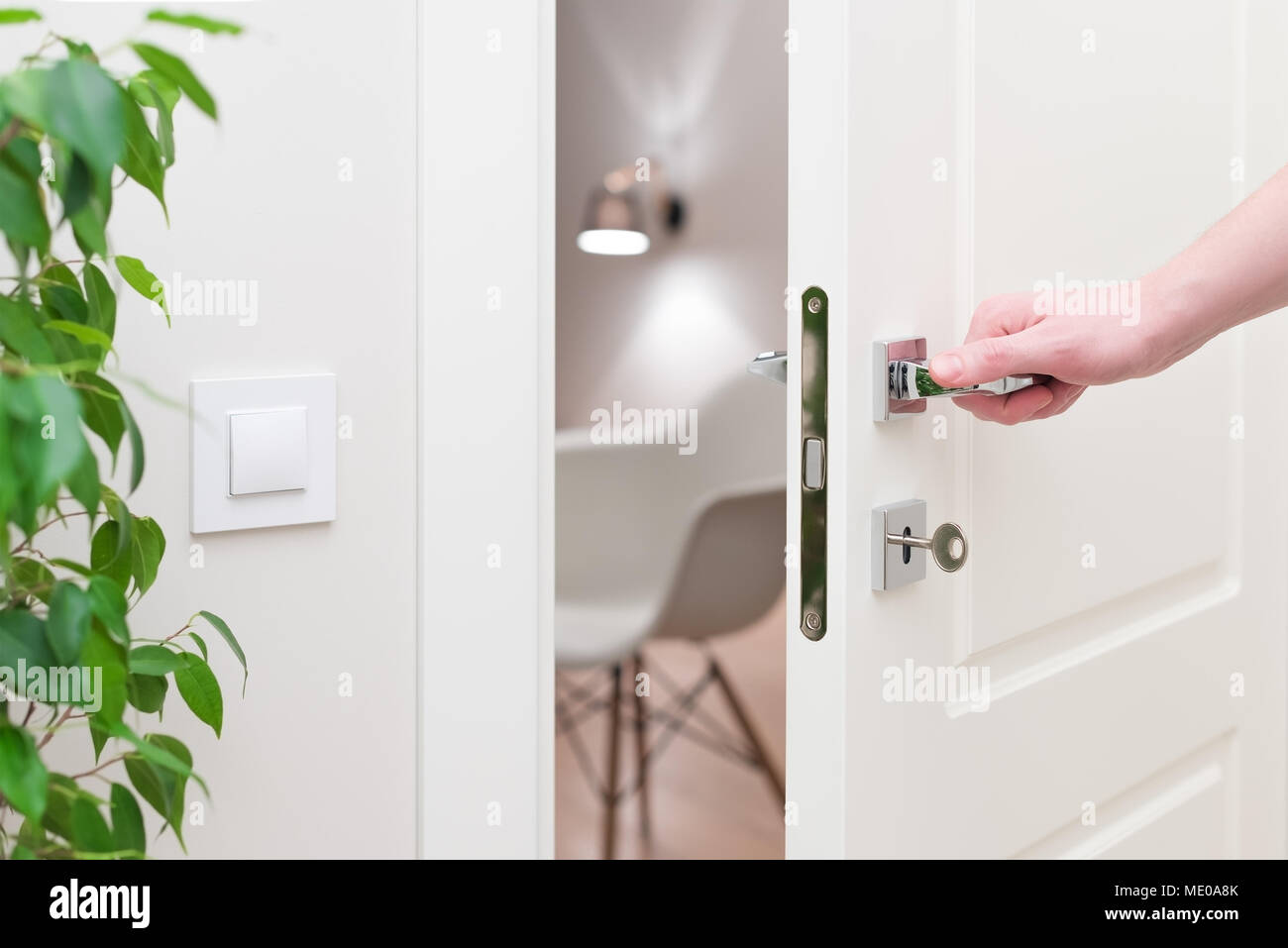 To open the door. Modern white door with chrome metal handle and a man's arm. Elements of interior closeup Stock Photo
