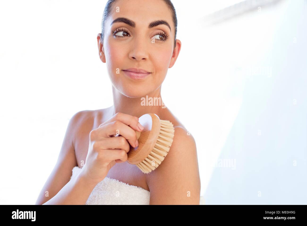 Young woman using body brush on shoulder. Stock Photo