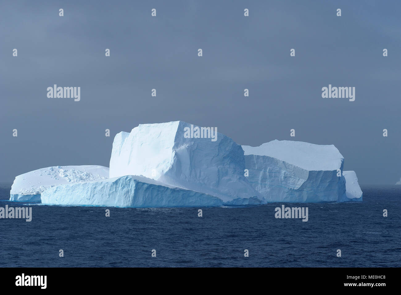 Sunlit iceberg in the dark blue waters of the Antarctic Sound at the Antarctic Peninsula, Antarctica Stock Photo