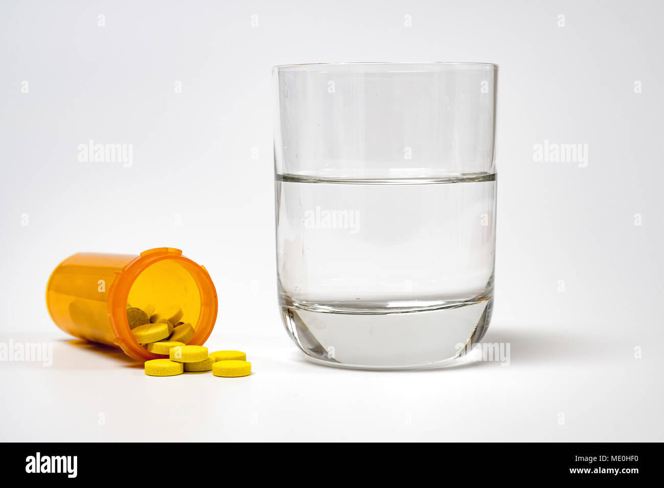 Medication and glass of water on a white background. Stock Photo