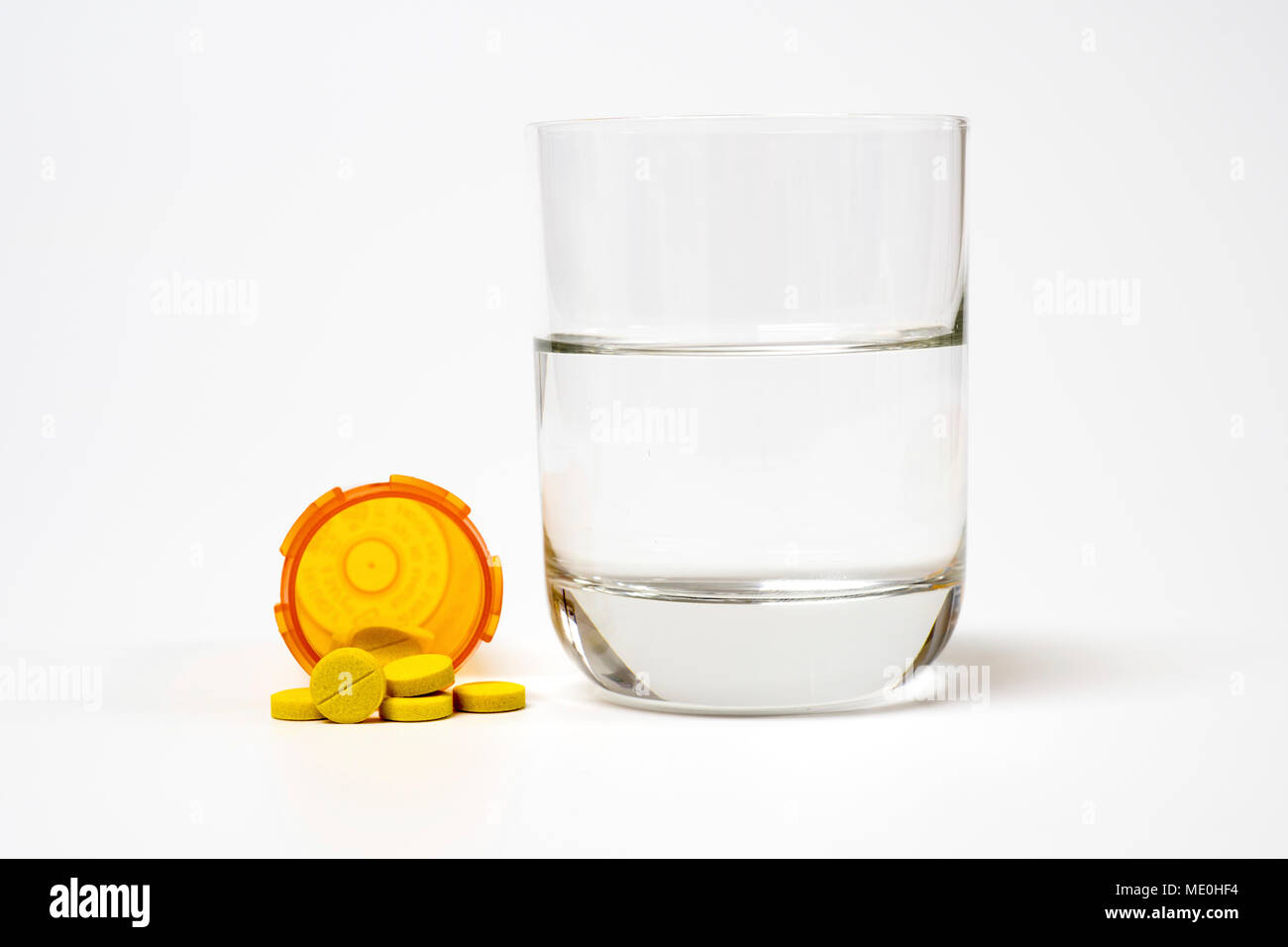 Medication and glass of water on a white background. Stock Photo