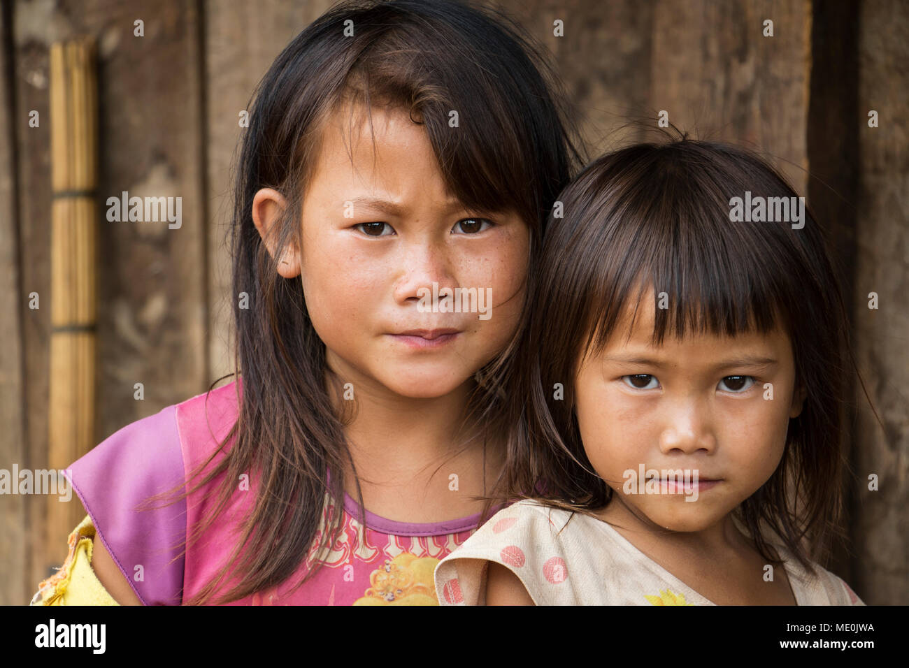 Portrait of two Hmong girls in front of their house in Na Kam Peng, also called Bomb Village; Xiangkhouang, Laos Stock Photo