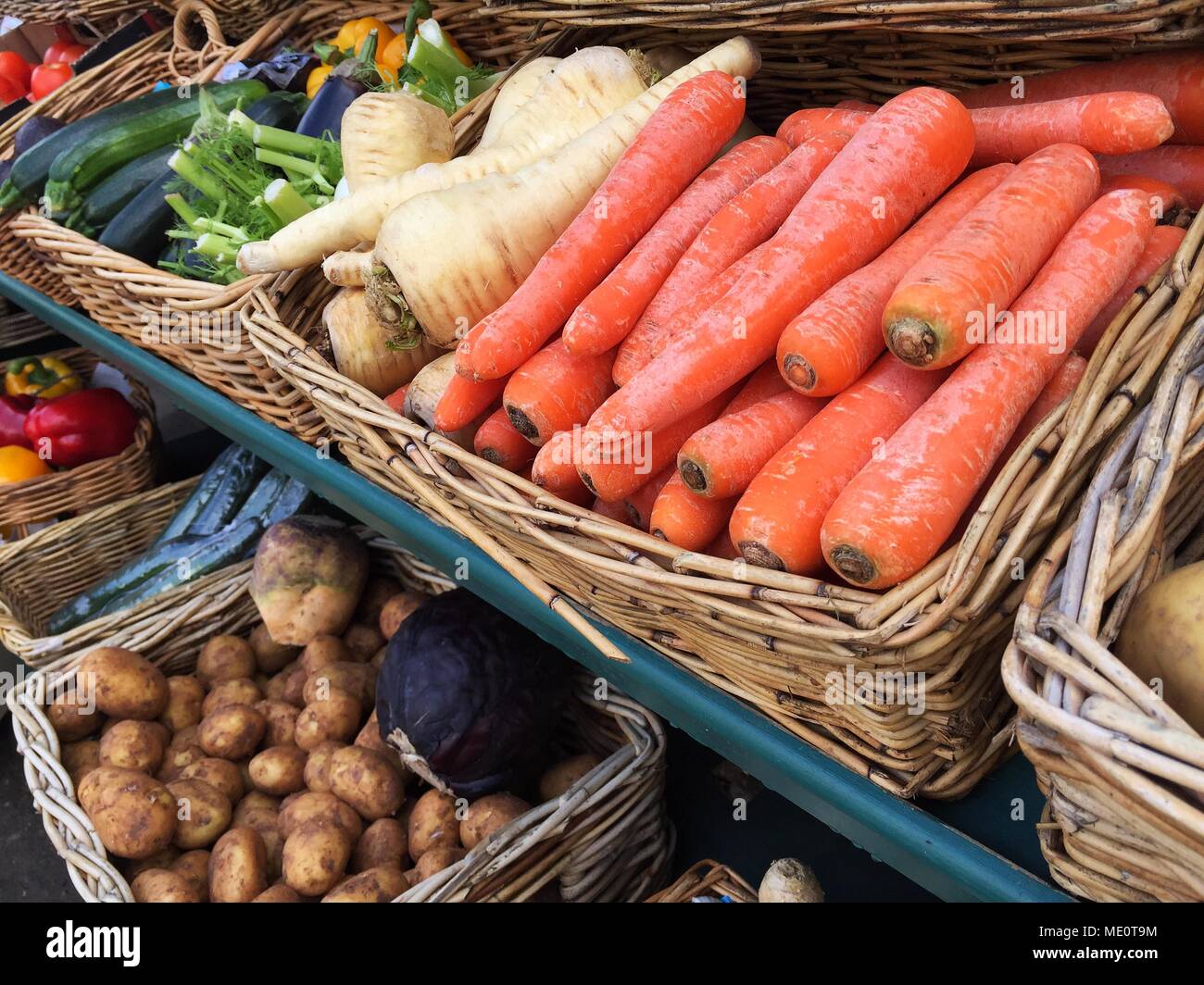 An outdoor market stall laden with a variety of fresh, organic fruit and vegetables including tomatoes, mushrooms and peppers. Stock Photo