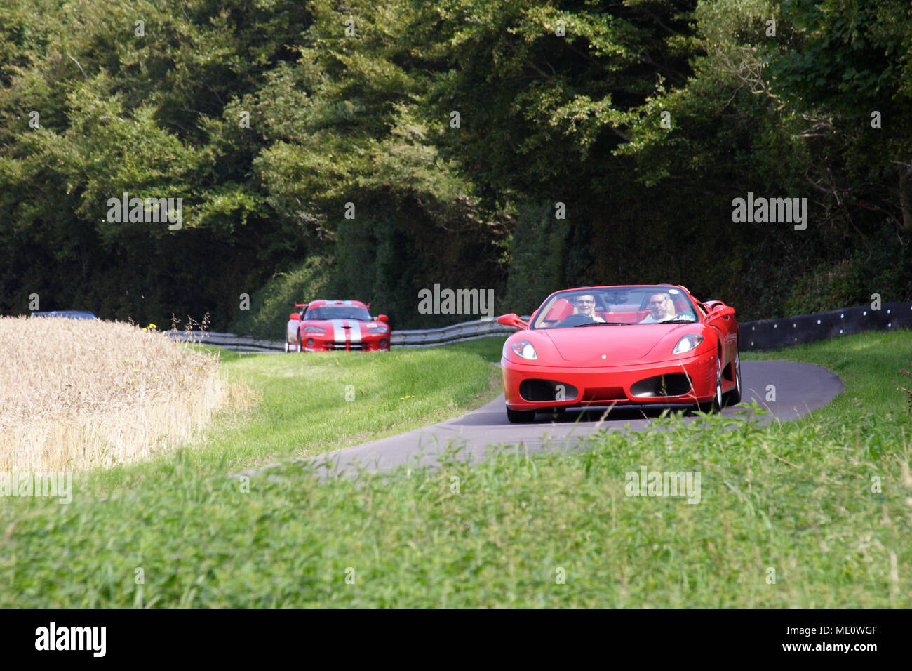 Red Ferrari 360 spider and red Dodge Viper road cars racing on track Stock Photo