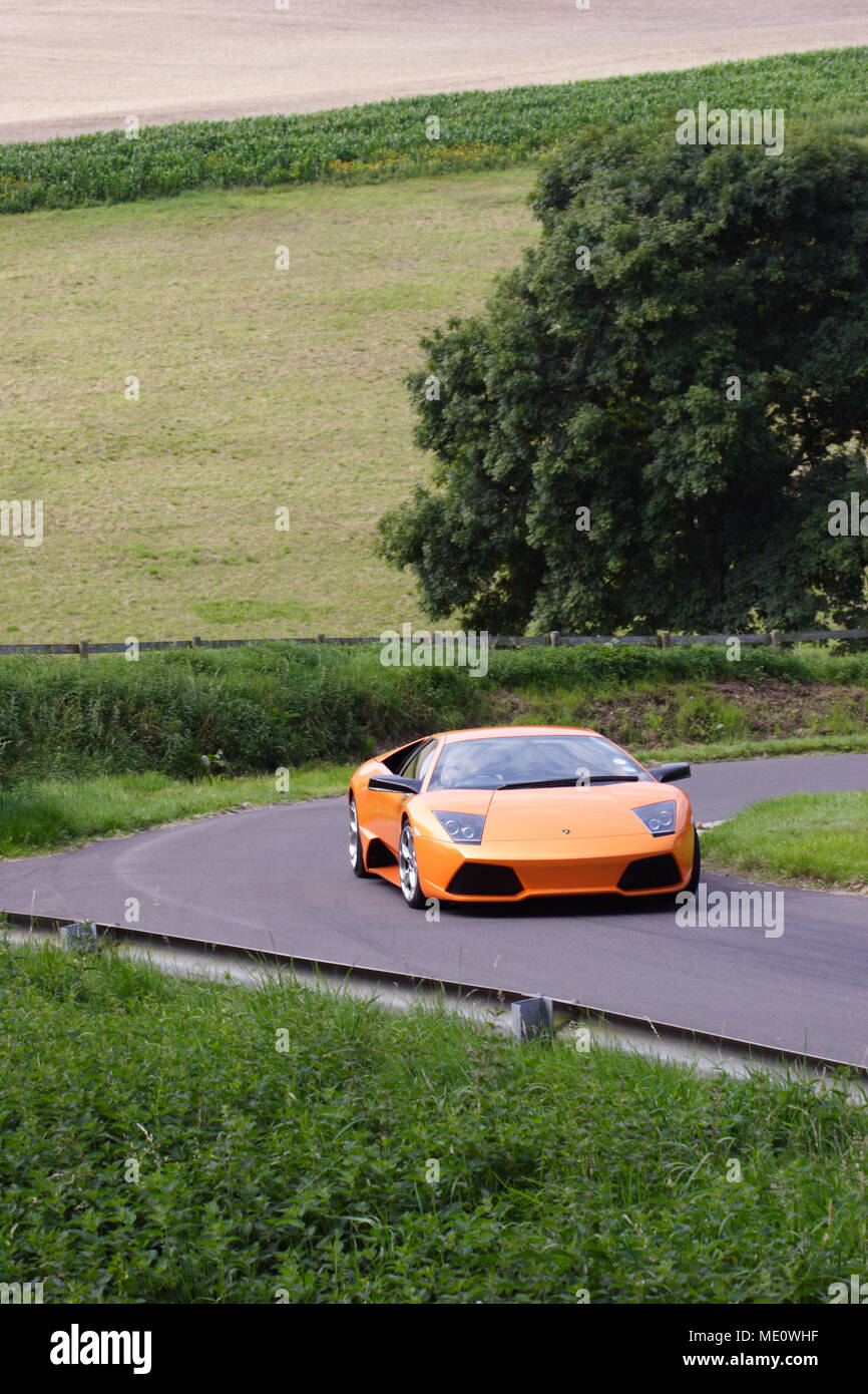 Orange Lamborghini Murcielago cornering and driving fast in the English countryside Stock Photo