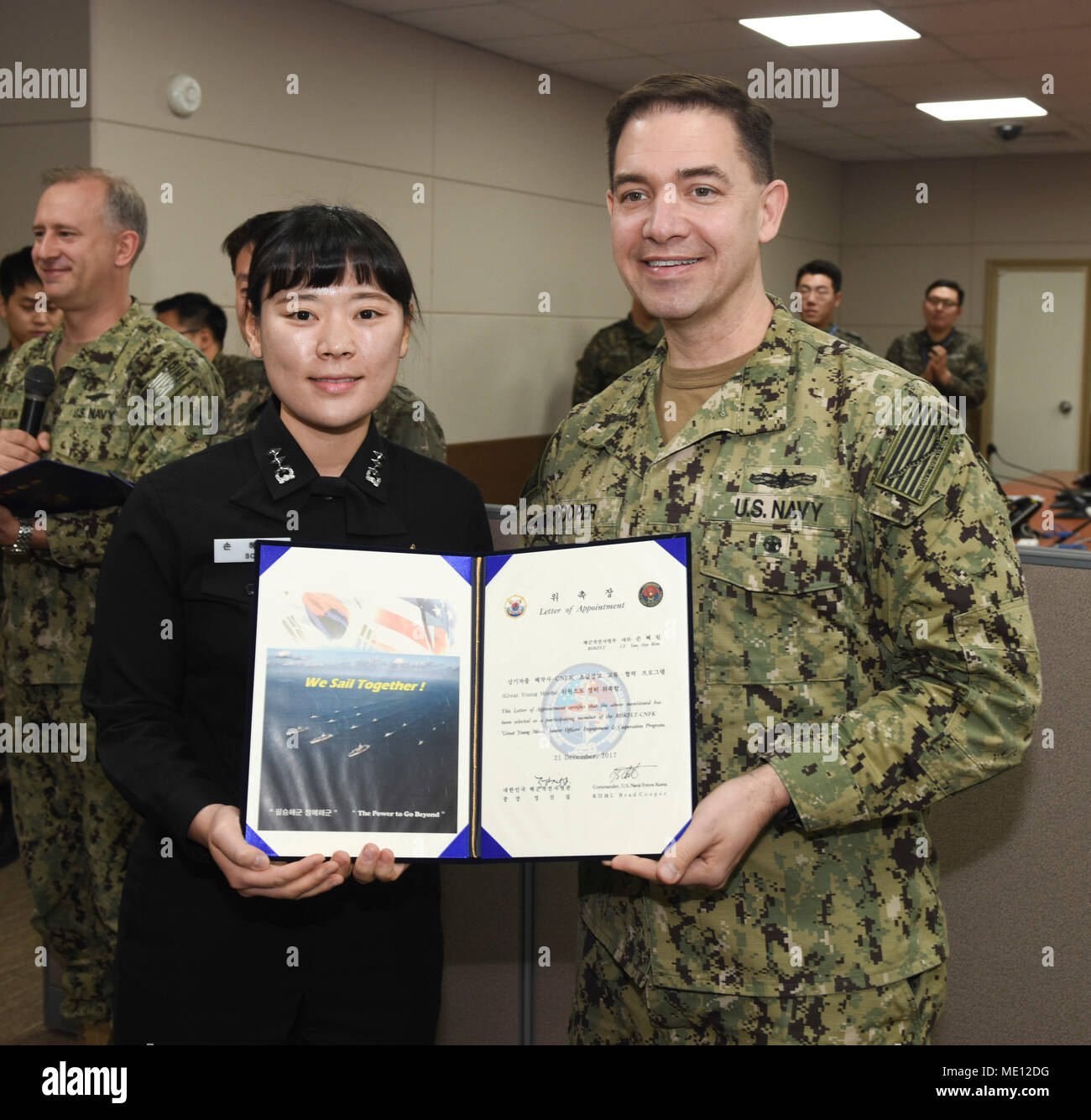 171221-N-TB148-056 BUSAN, Republic of Korea (Dec. 21, 2017) Rear Adm. Brad Cooper, commander, U.S. Naval Forces Korea (CNFK), presents Lt. Son, Hye Rim with a letter of appointment for her selection to the 'Great Young Minds' Junior Officers' Engagement and Cooperation Program. The 'Great Young Minds' initiative brings together hand-selected, young officers from the ROK and U.S. navies and challenges them to develop innovative solutions to further enhance the ROK -U.S. alliance of the future. (U.S. Navy photo by Mass Communication Specialist Seaman William Carlisle) Stock Photo