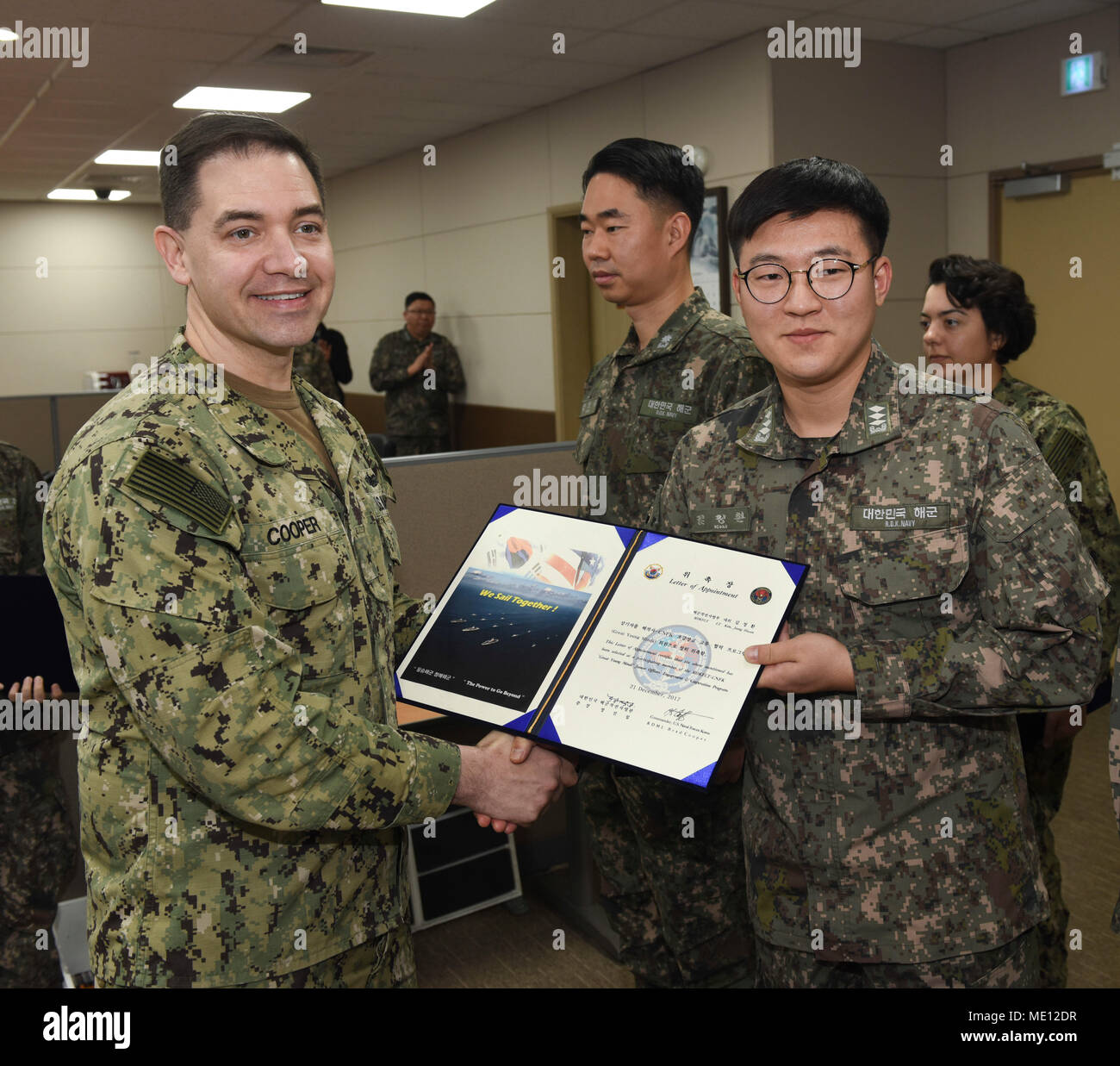 171221-N-TB148-033 BUSAN, Republic of Korea (Dec. 21, 2017) Rear Adm. Brad Cooper, commander, U.S. Naval Forces Korea (CNFK), presents Lt. Kim, Jeong Hwan with a letter of appointment for her selection to the 'Great Young Minds' Junior Officers' Engagement and Cooperation Program. The 'Great Young Minds' initiative brings together hand-selected, young officers from the ROK and U.S. navies and challenges them to develop innovative solutions to further enhance the ROK -U.S. alliance of the future. (U.S. Navy photo by Mass Communication Specialist Seaman William Carlisle) Stock Photo
