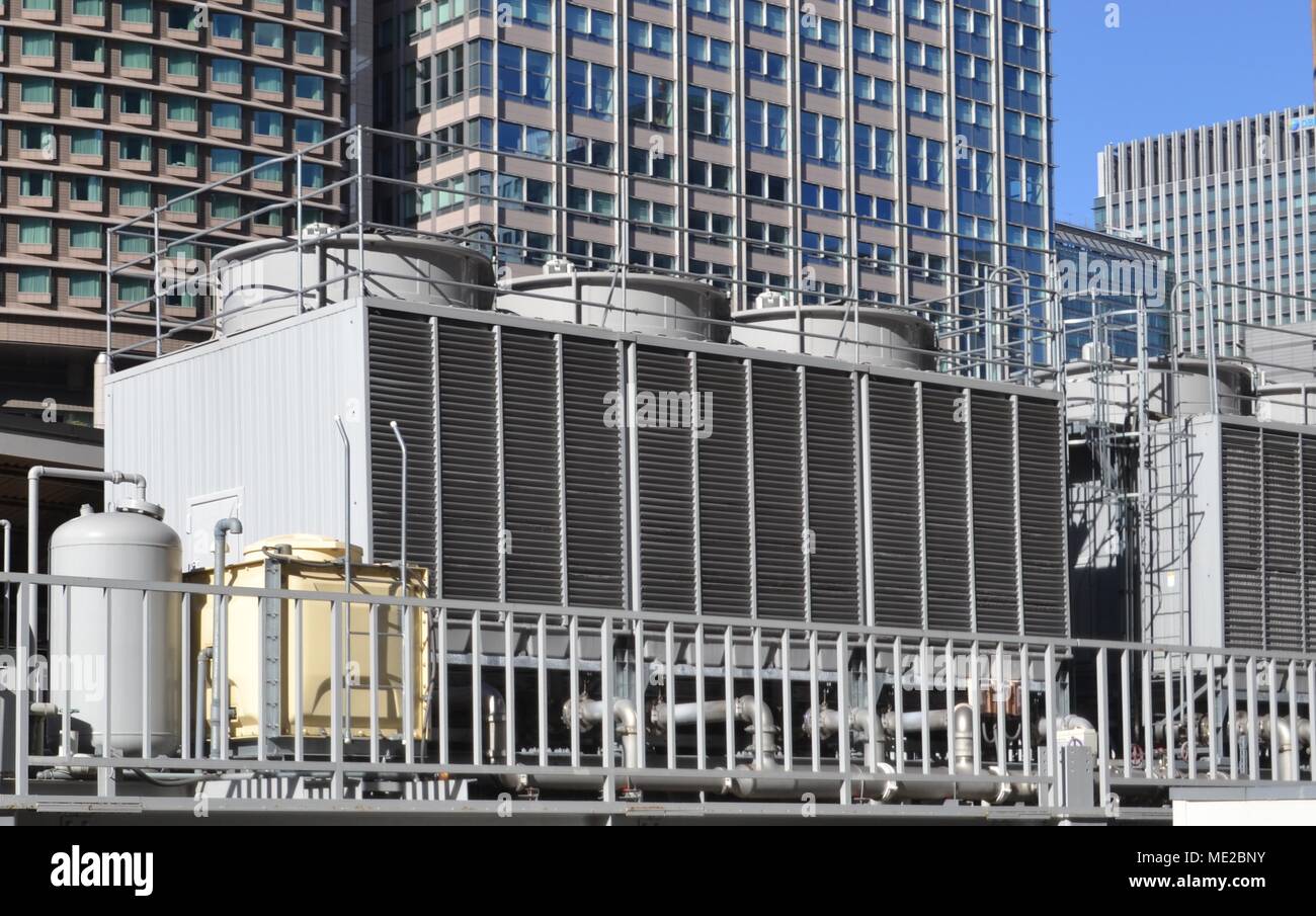 Air conditioning cooling tower unit in city, with office buildings in the background Stock Photo