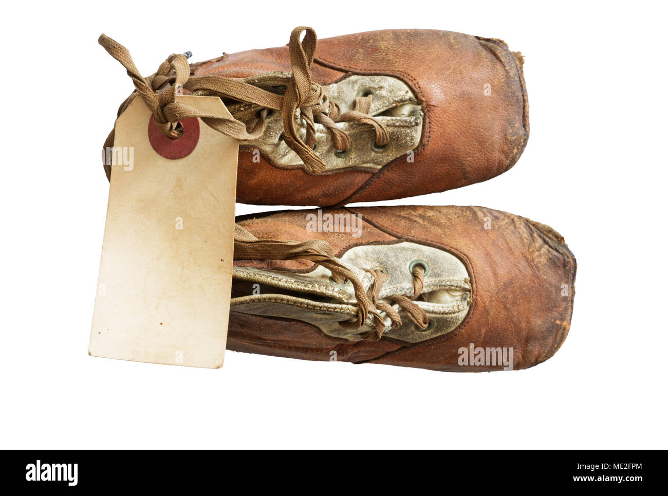 old worn baby shoes from 1908 with a blank paper tag tied onto the laces Stock Photo