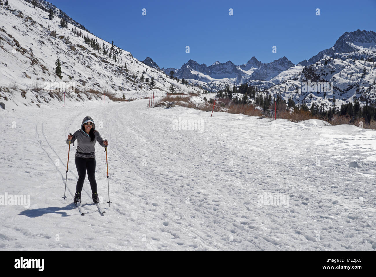 a woman cross country skiing down a snow covered road in the mountains Stock Photo