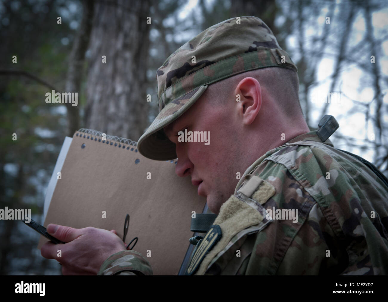 Specialist Dylan Hoover from the 492nd Engineer Company, 416th Theater Engineer Command (TEC), concentrates on accurately shooting an azimuth using the compass-to-cheek method prior to moving out to locate his assigned points during the Day Land Navigation event at the Devens Reserve Forces Training Area in Massachusetts April 17, 2018. Hoover and 17 other competitors from the 412th TEC, 416th TEC, 76th Operational Response Command, and the 99th Readiness Division are here taking a shot at the title of Best Warrior for their respective commands which would punch their ticket to the next round  Stock Photo