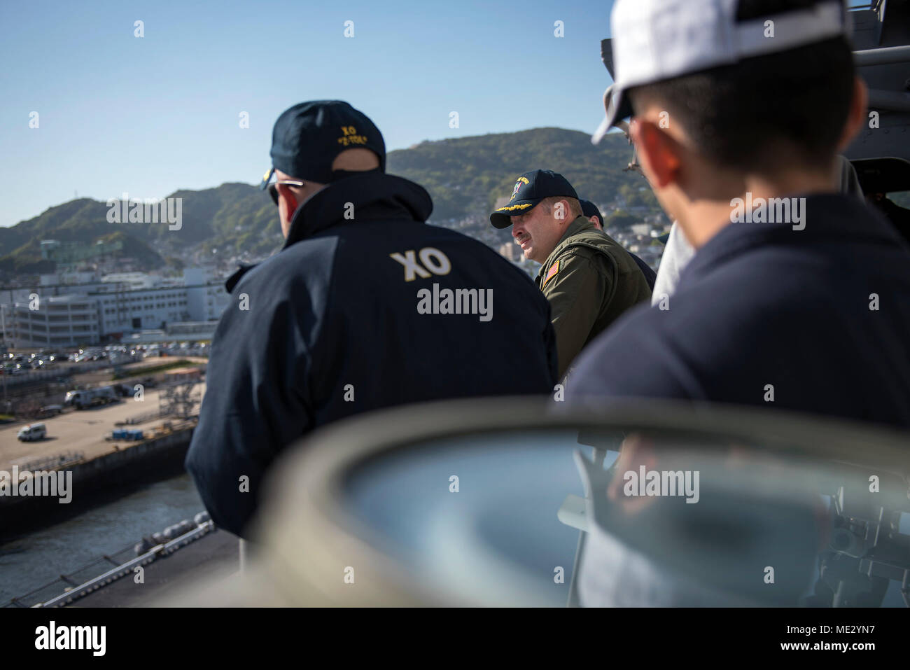 180418-N-WF272-226 SASEBO, Japan (April 18, 2018) Capt. Larry McCullen, center, commanding officer of the amphibious assault ship USS Bonhomme Richard (LHD 6), Capt. Richard Lebron, executive officer, and bridge officers observe pier operations as the ship departs Sasebo, Japan for the last time. Bonhomme Richard has been the flagship of the Amphibious Force 7th Fleet since April 2012 and will now transit to its new homeport in San Diego for follow-on operations and eventual upgrades to become F-35B Lightning II capable. (U.S. Navy photo by Mass Communication Specialist 2nd Class Diana Quinlan Stock Photo