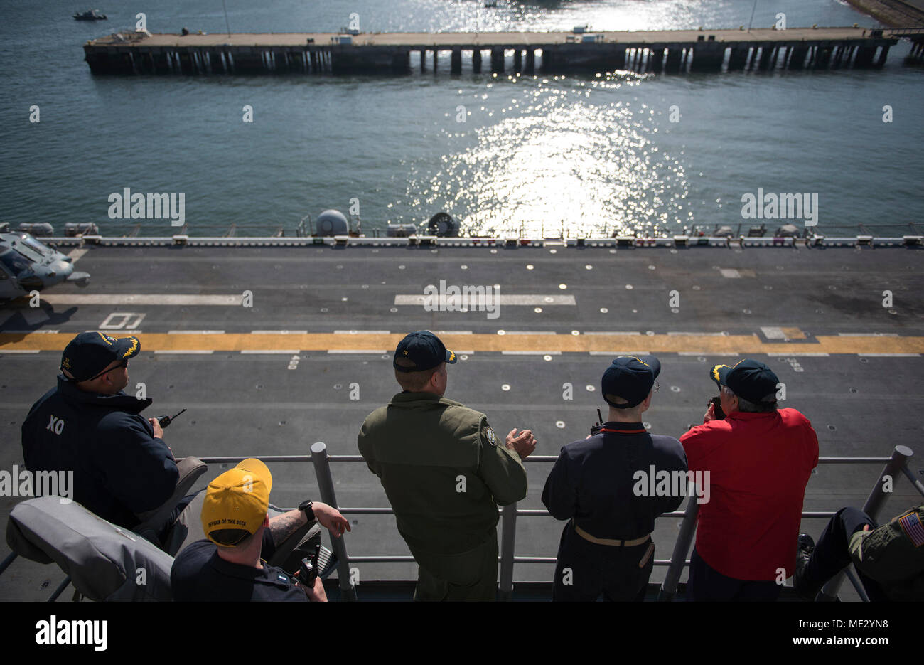 180418-N-WF272-231 SASEBO, Japan(April 18, 2018) Capt. Larry McCullen, center, commanding officer of the amphibious assault ship USS Bonhomme Richard (LHD 6), Capt. Richard Lebron, executive officer, and bridge officers observe pier operations as the ship departs Sasebo, Japan for the last time. Bonhomme Richard has been the flagship of the Amphibious Force 7th Fleet since April 2012 and will now transit to its new homeport in San Diego for follow-on operations and eventual upgrades to become F-35B Lightning II capable. (U.S. Navy photo by Mass Communication Specialist 2nd Class Diana Quinlan/ Stock Photo