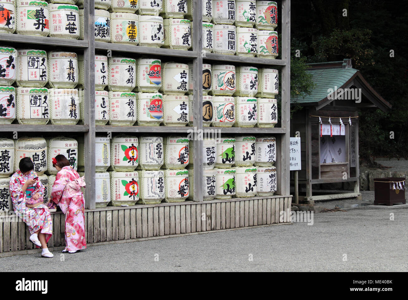 Translation girls in kimono in front of drums or barrels of sake (Japanese alcoholic drinks) at