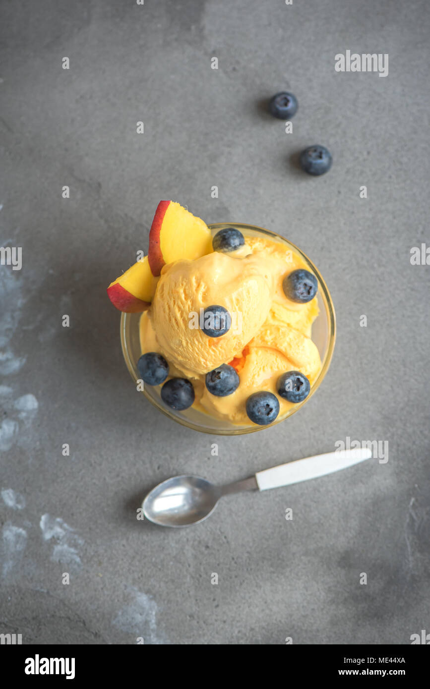 Mango Ice Cream or Sorbet with Blueberries in bowl. Homemade fruit mango ice cream on gray background, copy space. Stock Photo