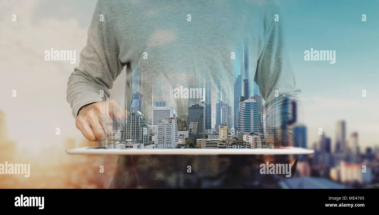 a man using digital tablet, and modern buildings hologram. Real estate business and building technology concept Stock Photo