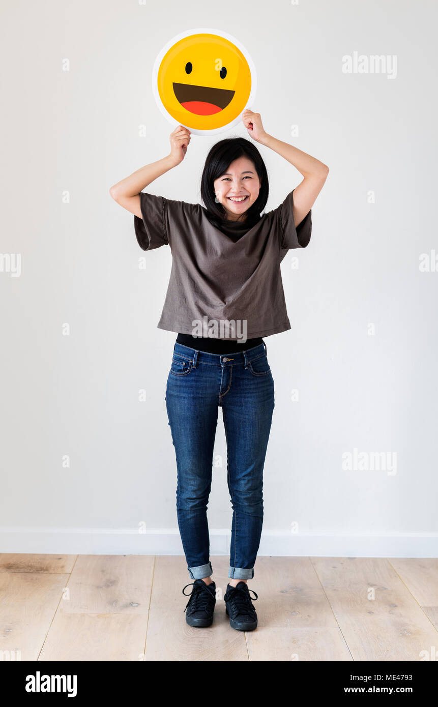 Happy Asian woman holding a smiley emoticon face Stock Photo