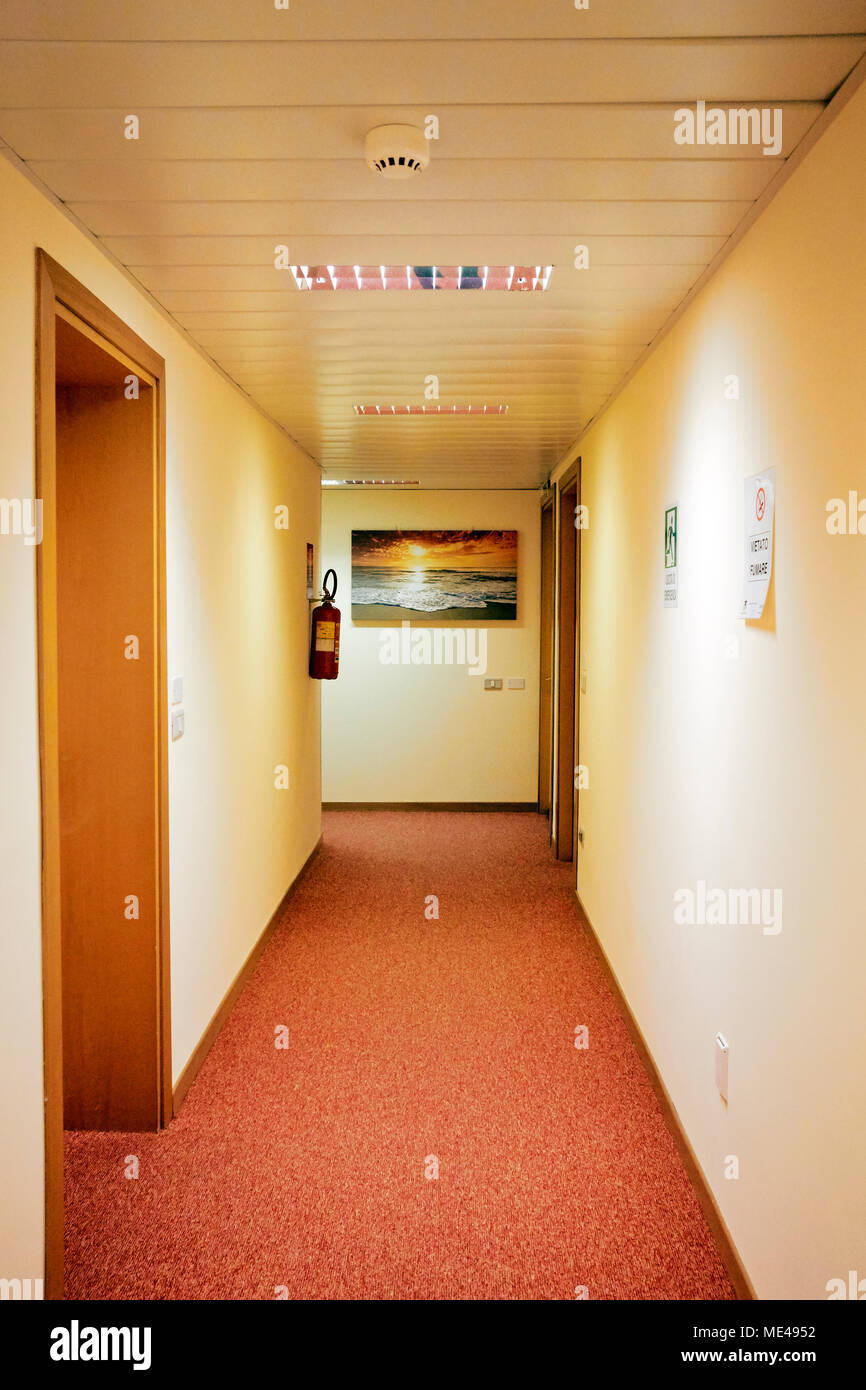 Sunset corridor - An empty hotel corridor in orange with a sunset photo and fire extinguisher Stock Photo