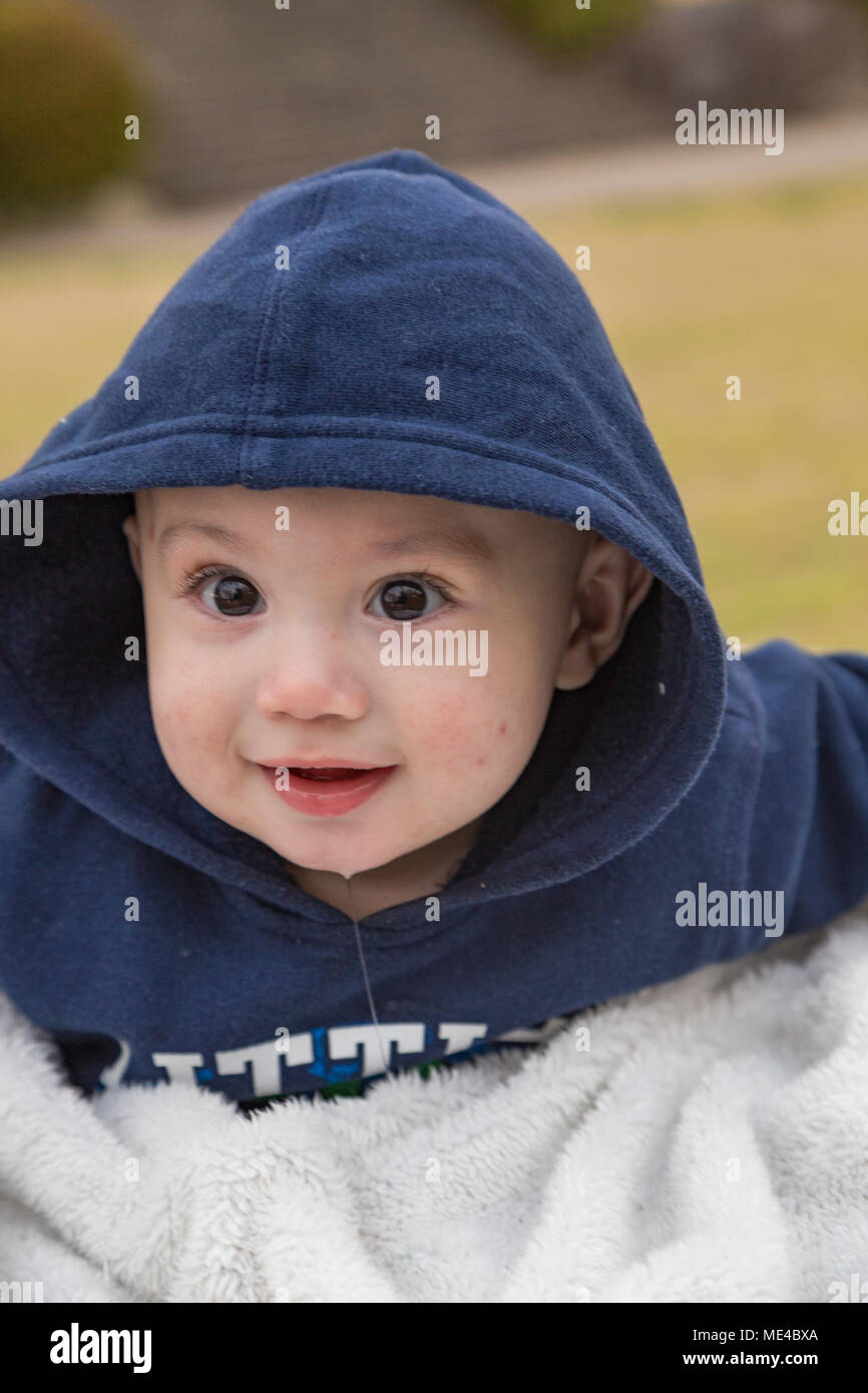 Baby boy in hoodie with big eyes at the park. Stock Photo