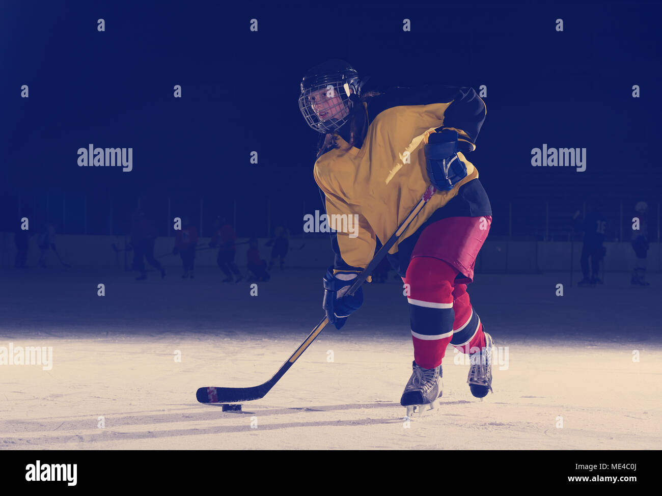 teen girl children ice hockey player in action kicking puck with stick
