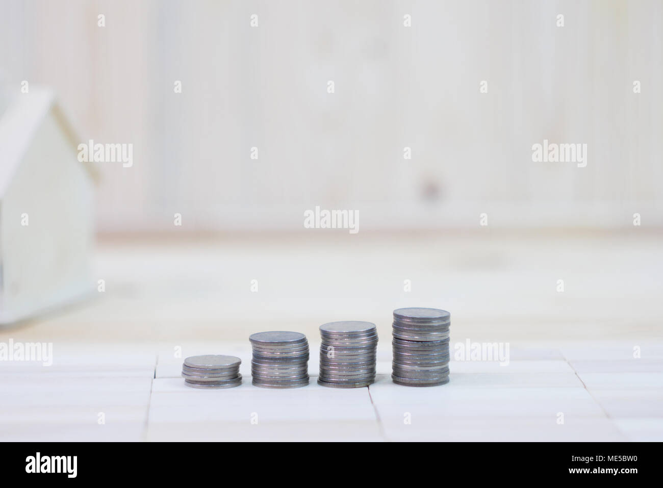 coins stack and house is located on a wooden floor Stock Photo