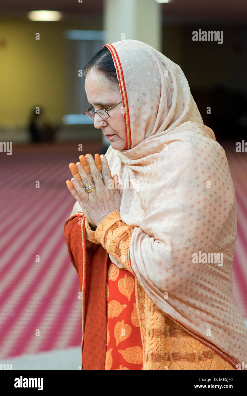 Portrait of a Sikh woman with orange fingers meditating at a wedding at the Gurdwara Sikh Cultural Society in South Richmond Hill, Queens, New York Stock Photo