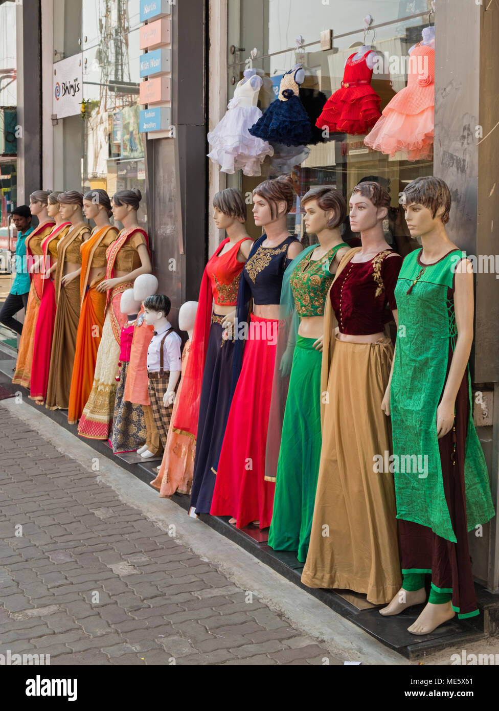 Mysore, India - March 3, 2018: An unidentified youth standing at the end of a row of mannequins outside a clothing store in the city centre Stock Photo
