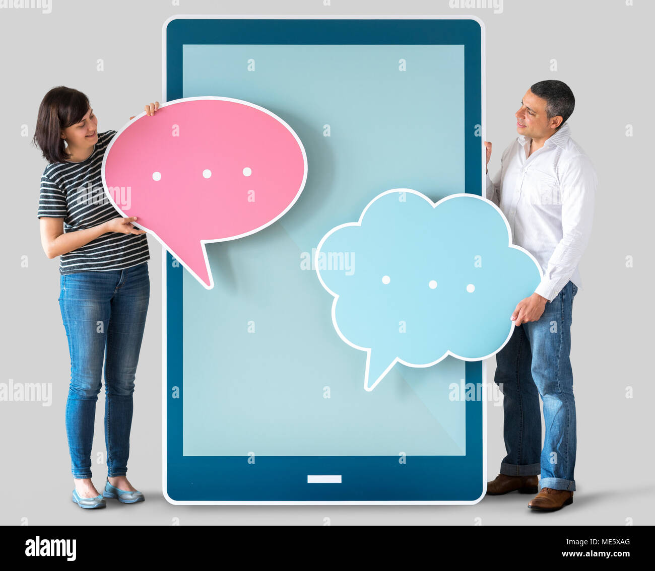 Diverse people holding speech bubbles and tablet Stock Photo