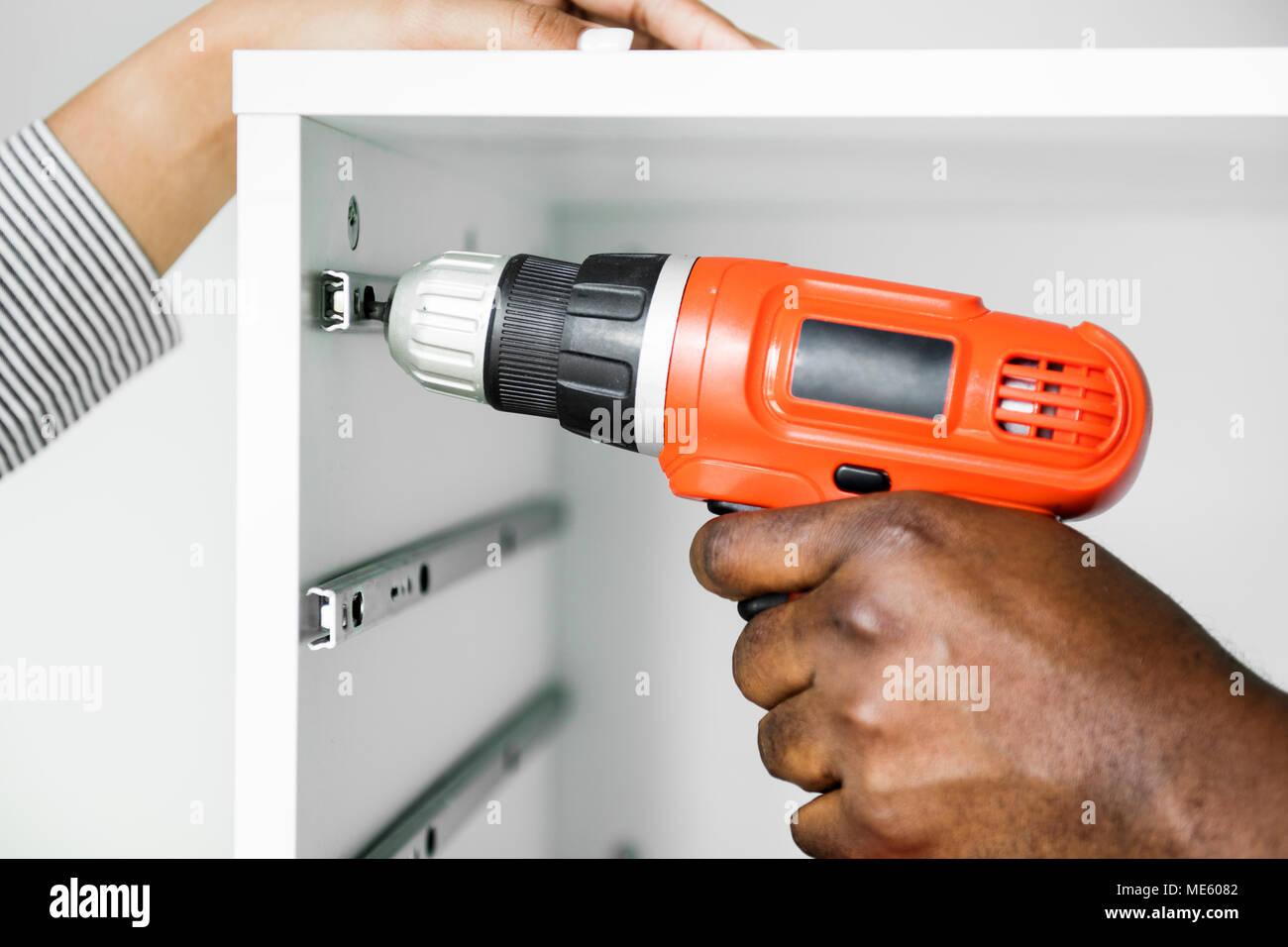 Man using electronic drill install cabinet Stock Photo