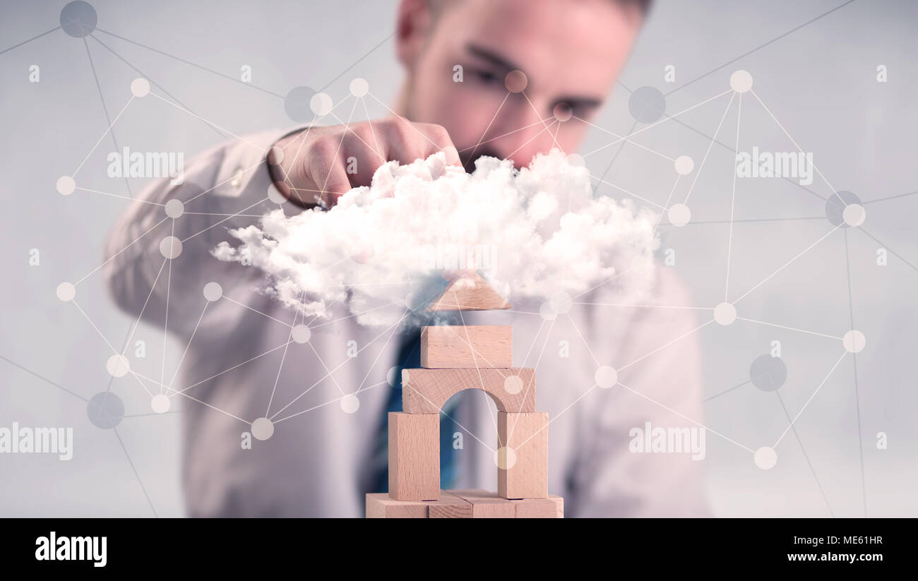Young handsome businessman using wooden building blocks behind cloud ...