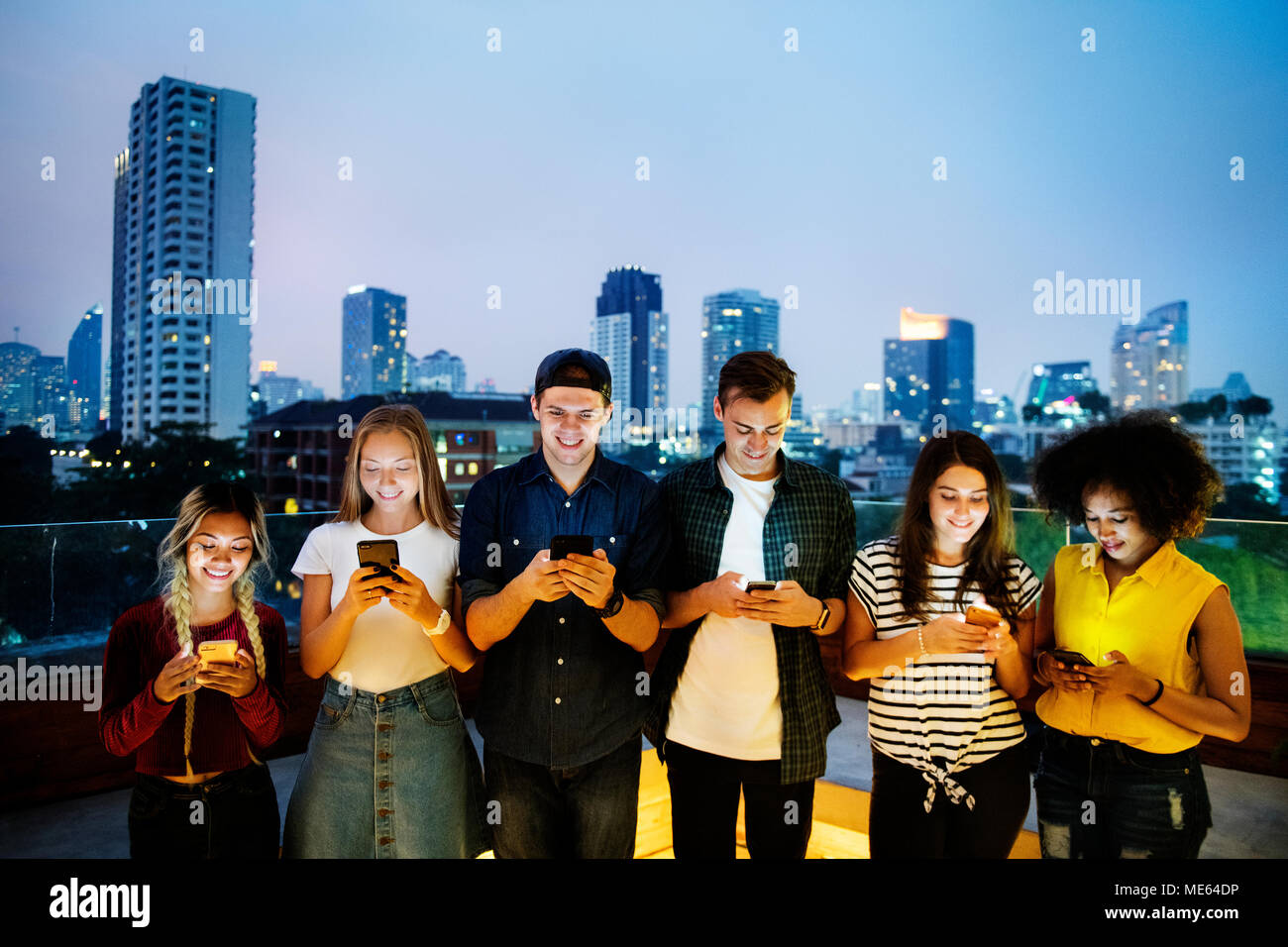 Happy group of young adults using smartphones in the cityscape Stock Photo