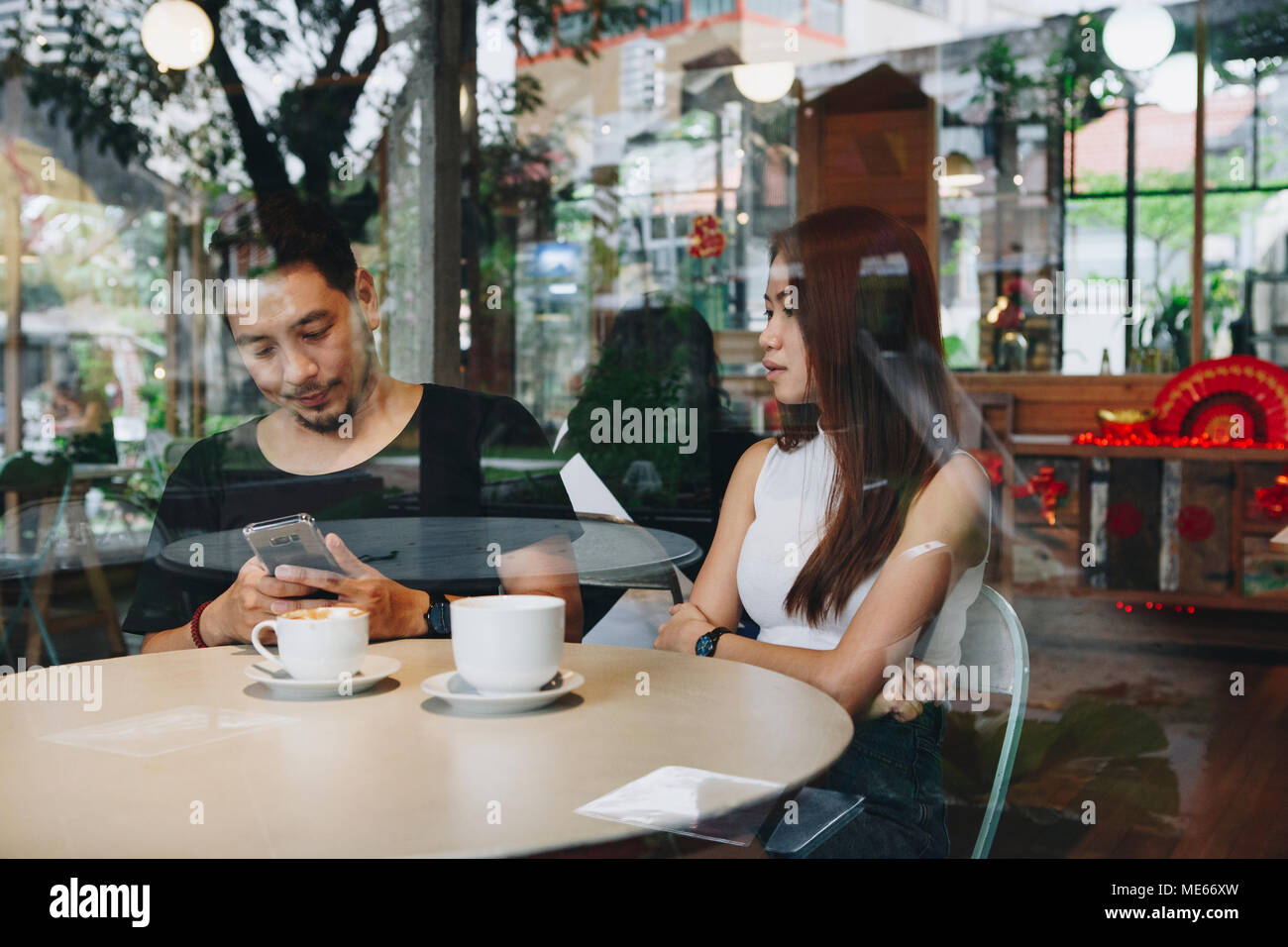 Couple using a phone at a cafe Stock Photo