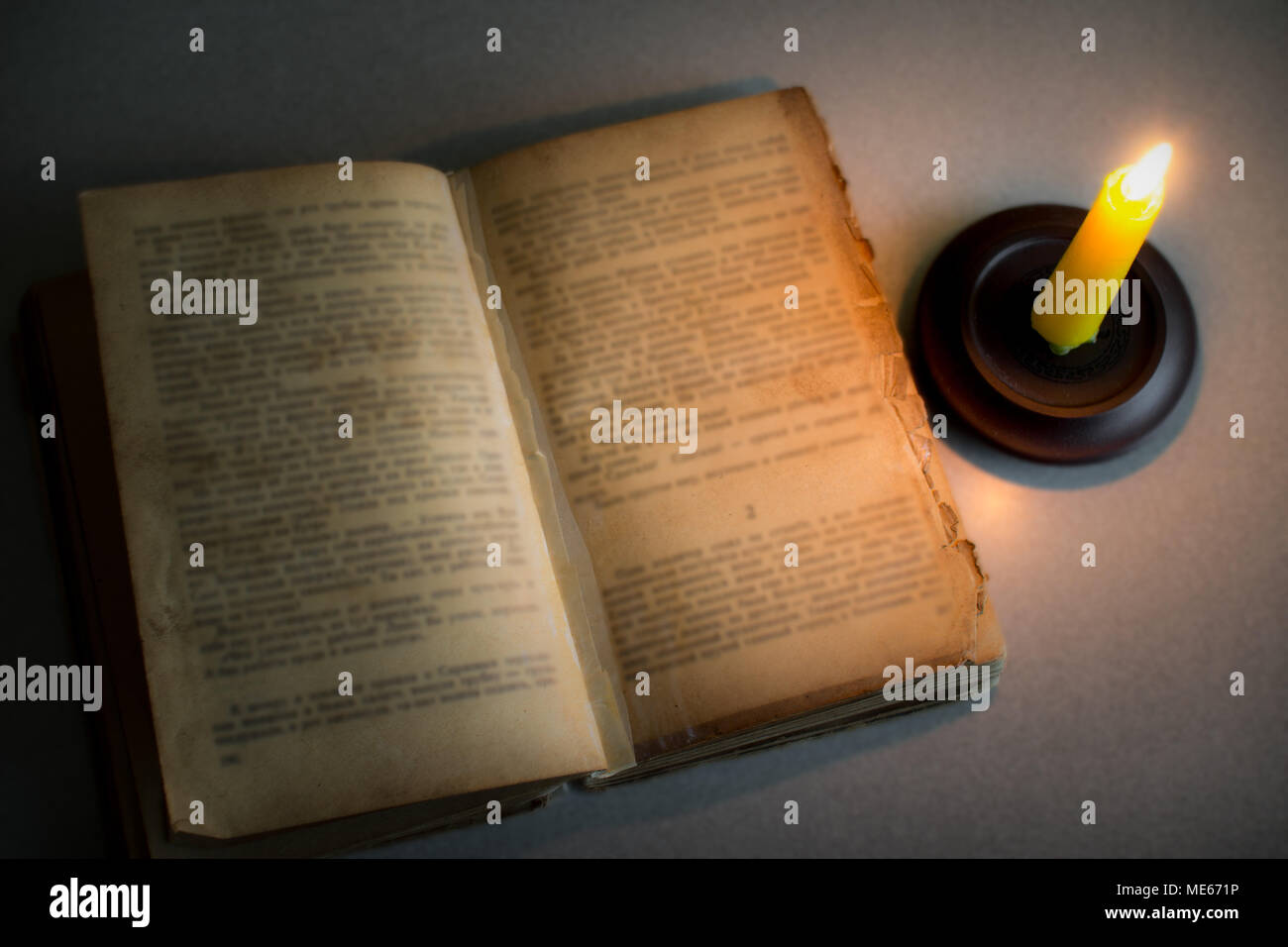 Old open book on table by candlelight. book and burning candle. top