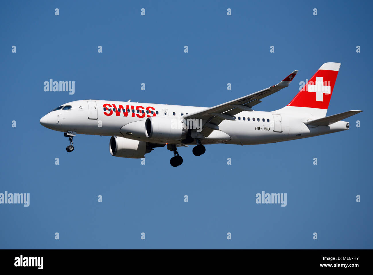 Swiss airline Bombardier CSeries CS100 jet plane coming in to land at London Heathrow Airport, UK, in blue sky. C Series HB-JBD Stock Photo