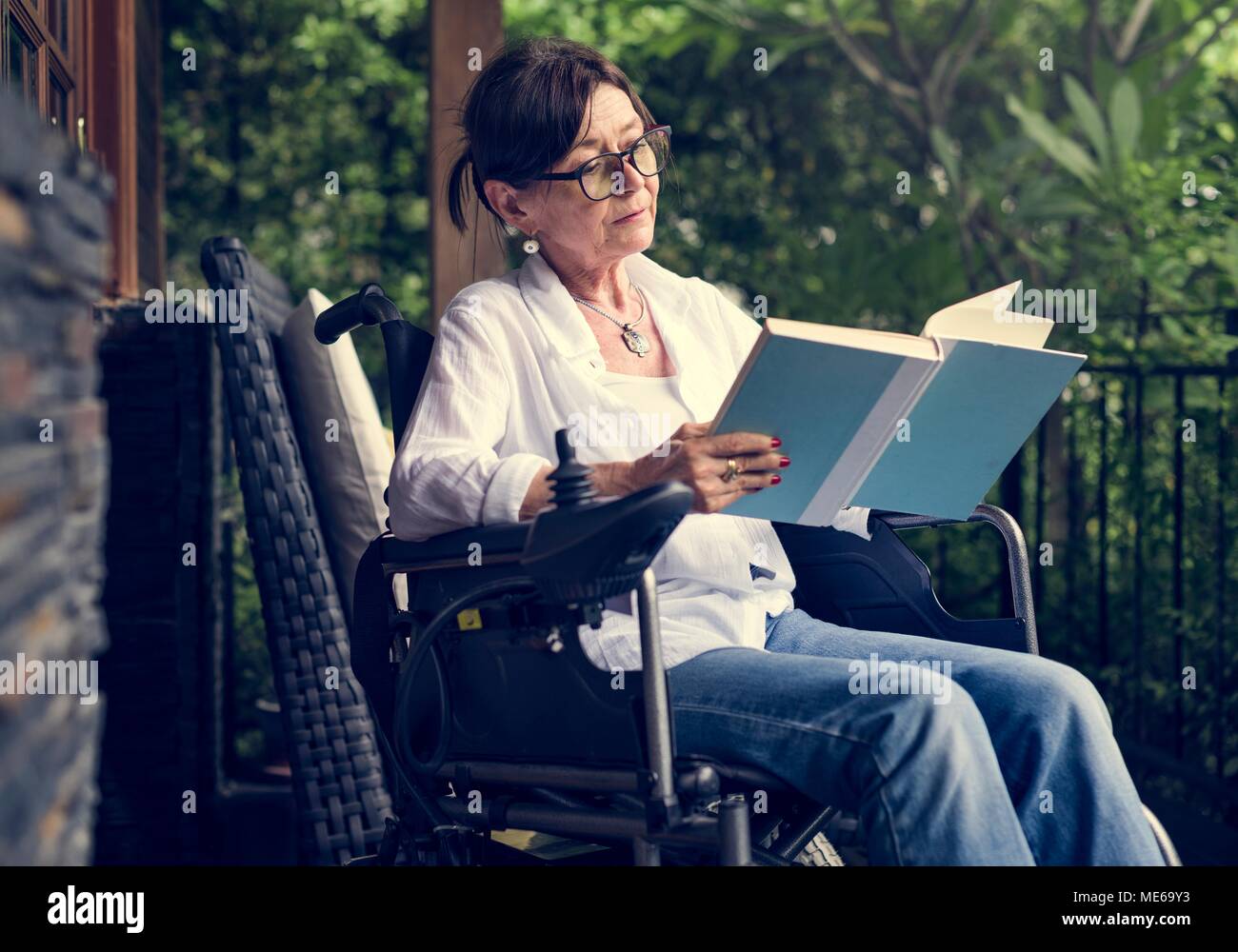 Woman reading a book in a wheelchair Stock Photo