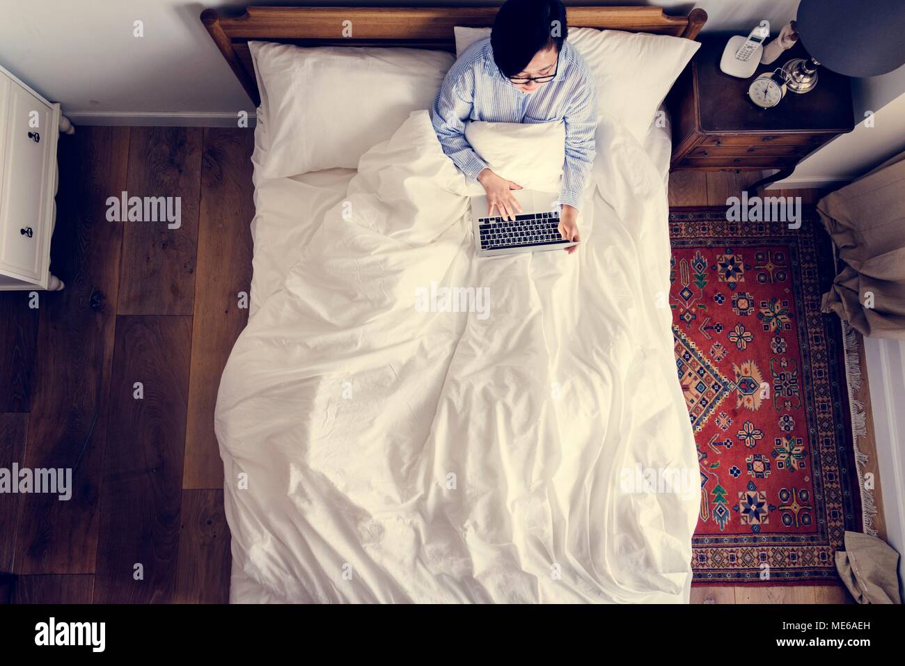 Woman in bed using a digital device Stock Photo