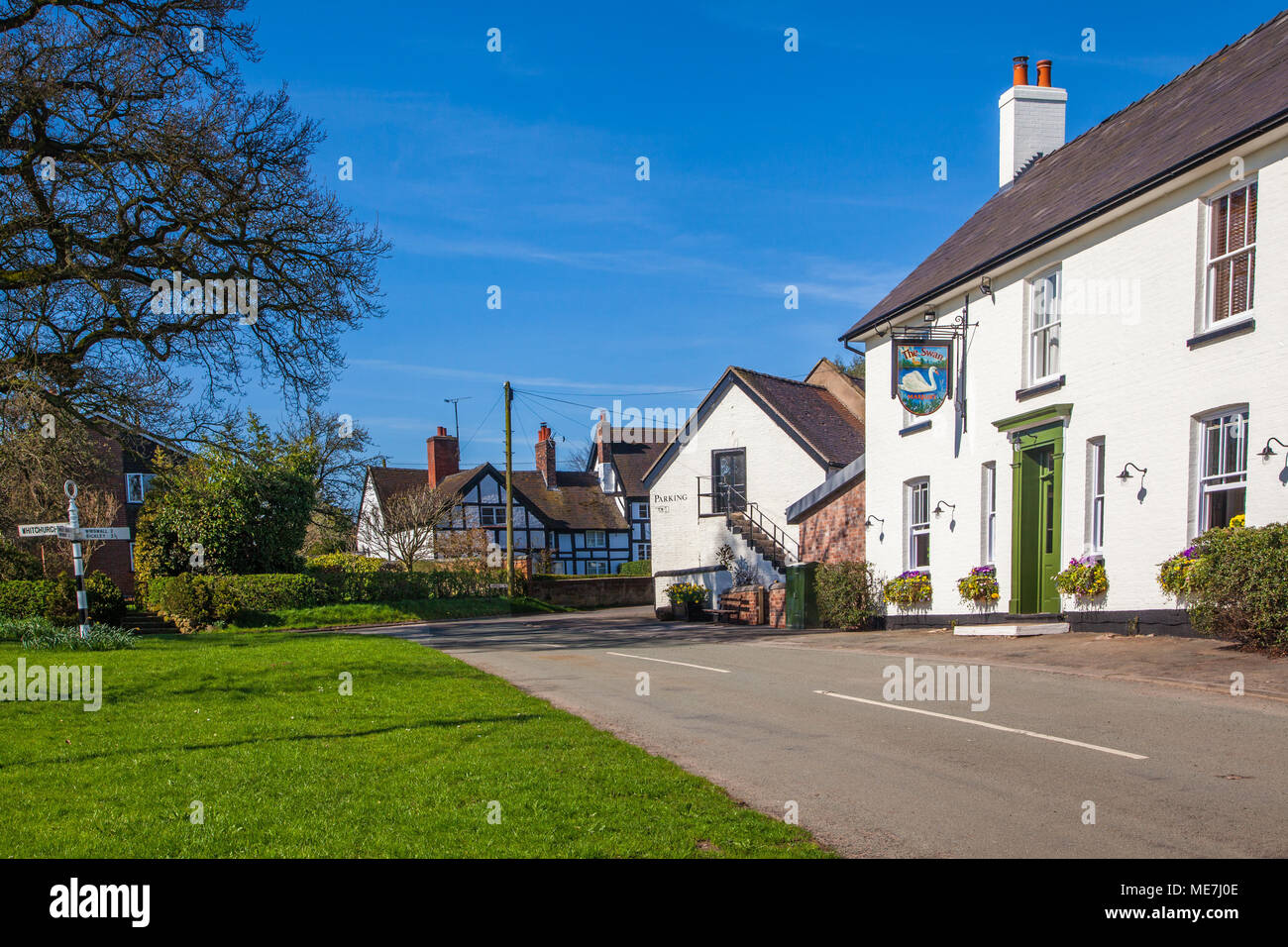 The village green and the Swan inn / public house at the South Cheshire rural countryside village of Marbury with black and white half timbered houses Stock Photo