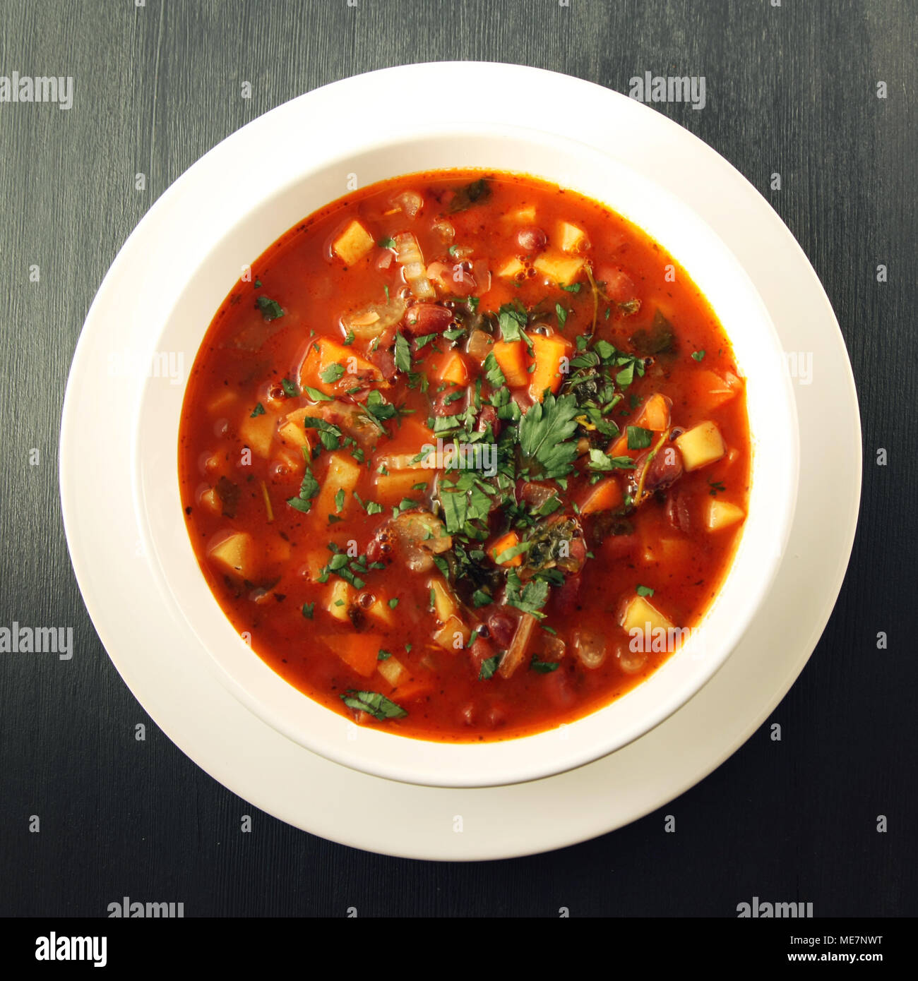Tomato soup with red beans, potato and carrot. Vegan diet. European cuisine. Vegetarian dish. Main course. Organic meal. Toned photo. Top view. Stock Photo