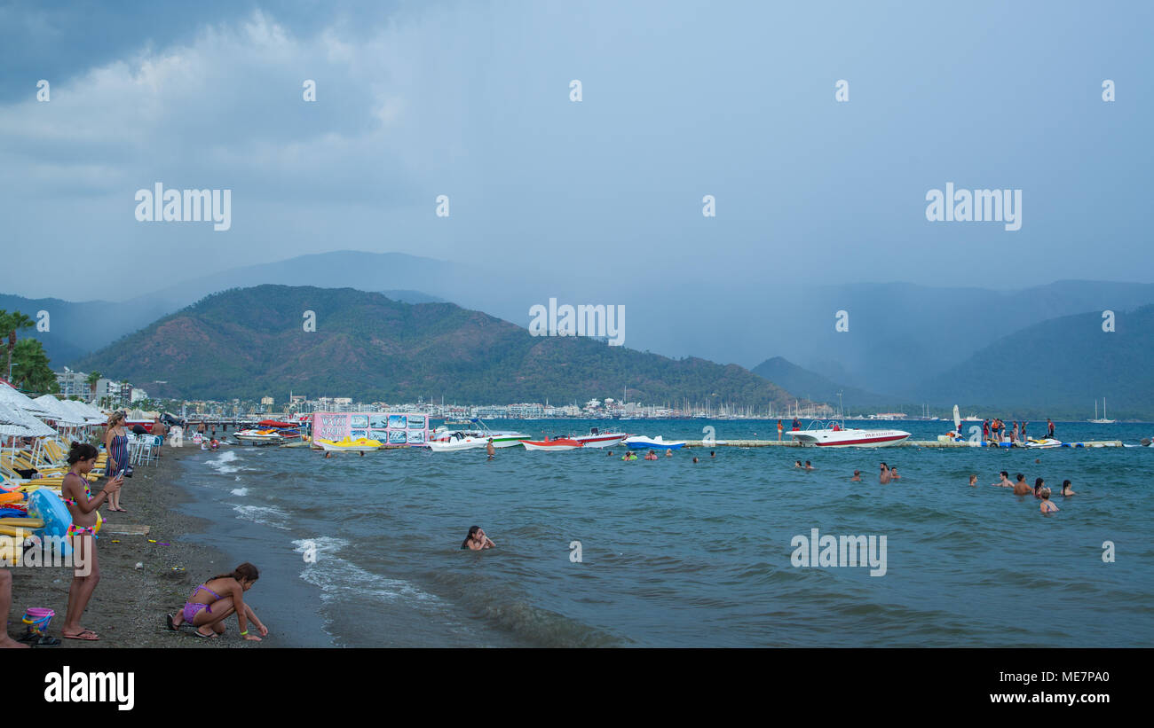 People bathe in the sea against a background of rain in the mountains, Marmaris, Turkey Stock Photo