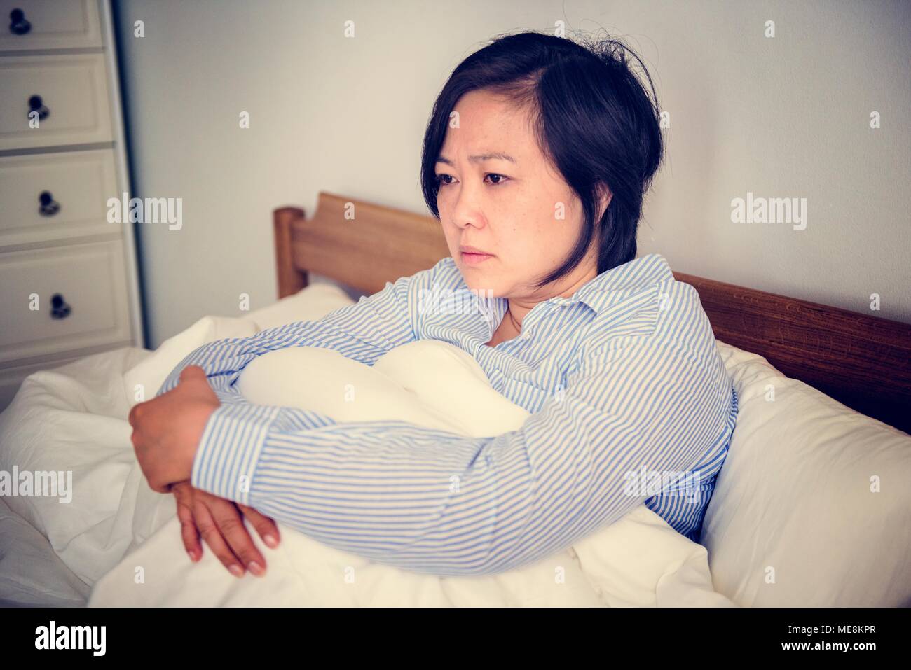 An upset woman pondering in bed Stock Photo