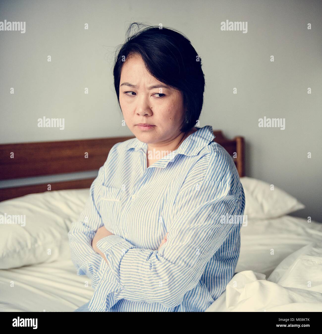 An upset woman in a bed room Stock Photo