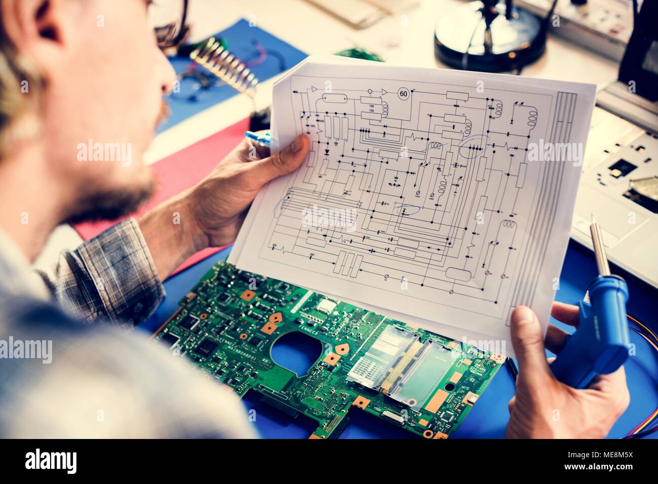 Technician studying electronics circuit guideline paper Stock Photo